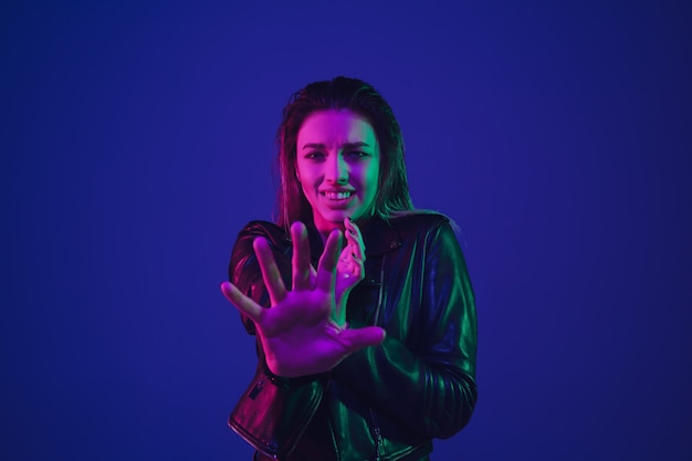 Caucasian woman's portrait isolated on blue studio background in neon light