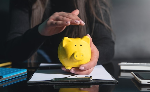 Caucasian woman showing a piggy bank on the table