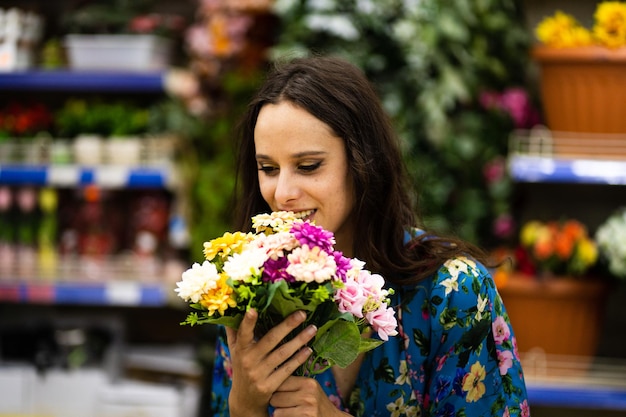 Caucasian woman smelling flowers from a bucket in a florist shop