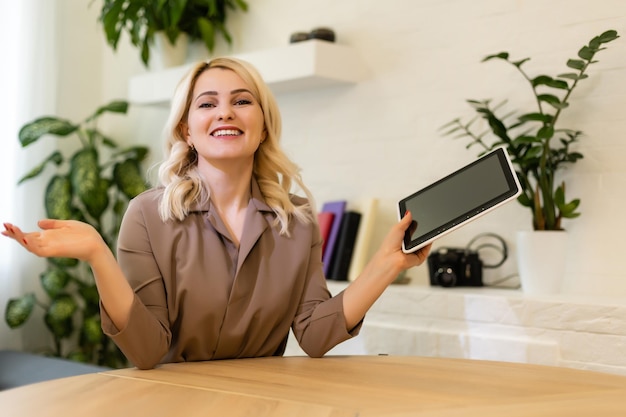 Caucasian woman smiling and showing the screen of her tablet