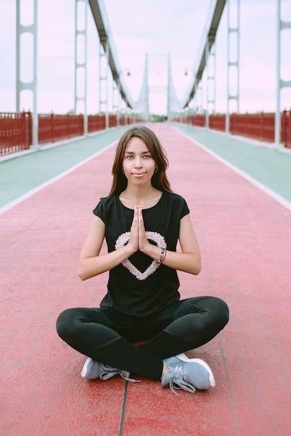 caucasian woman in sportswear and sneakers sitting in lotus pose