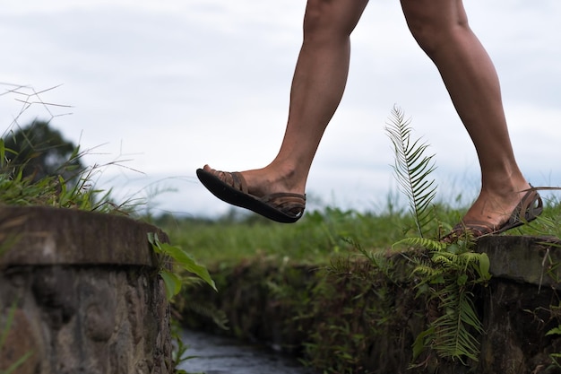 Caucasian woman step over the water ditch Se has an active vacation in asia and goes for a walk