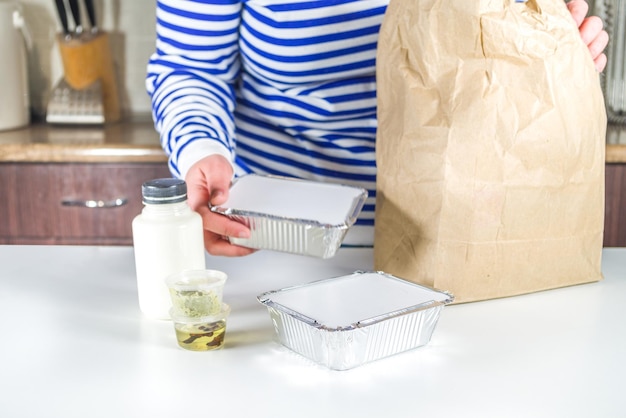 Caucasian woman take apart package with Heat-and-eat meal boxes from the restaurant. Takeout order delivery service food concept, close-up