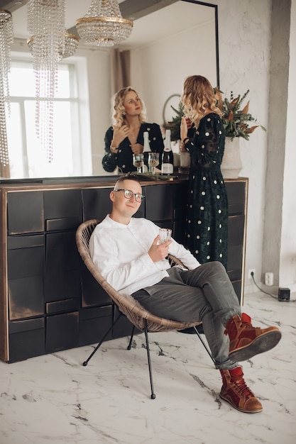 Caucasian woman touches her hair and a man sits on the armchair