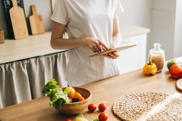 La donna caucasica utilizza il computer tablet in cucina a preparare l'insalata di leggere la ricetta