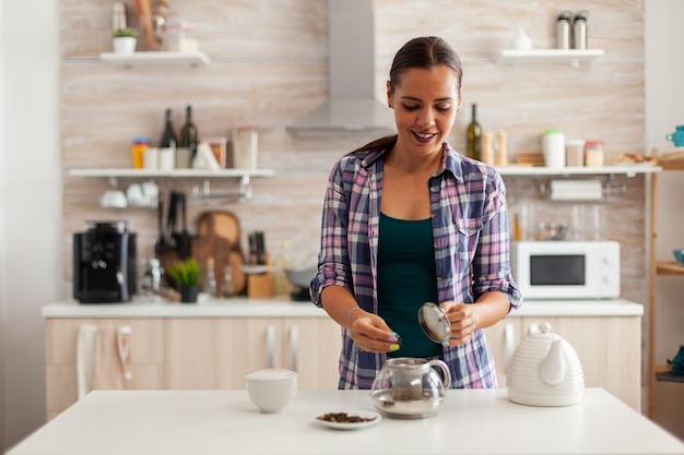 Donna caucasica che usa erbe aromatiche per preparare il tè caldo al mattino