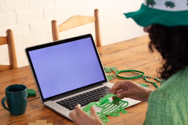 Photo caucasian woman using computer dressed in green costume for st patrick's day video call