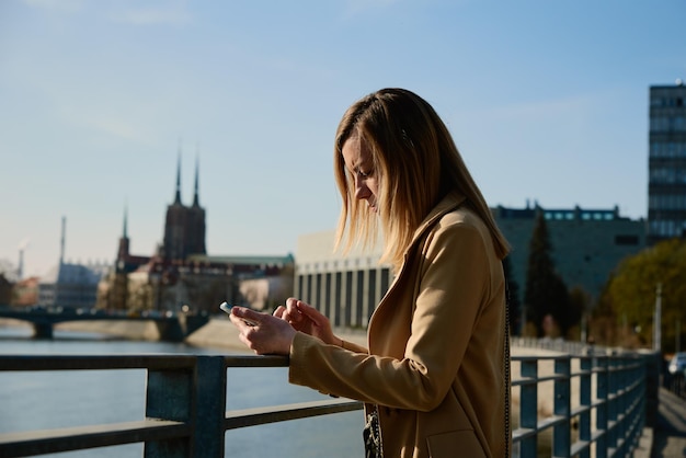 街の通りでsmartphineを使用している白人女性