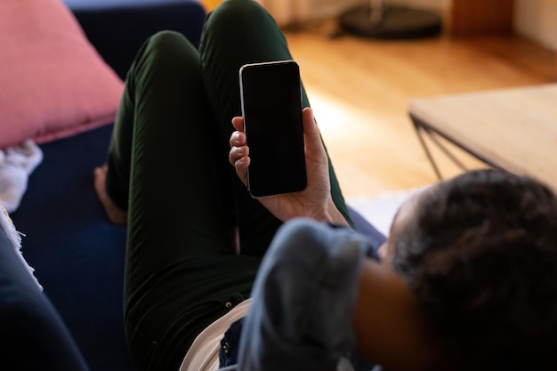 caucasian woman using smartphone lying on sofa at home