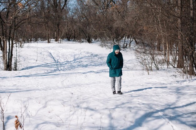 白人女性が雪に覆われた森の中を歩く冬の暖かい服を着た若い女性は、勝利の散歩を楽しんでいます...