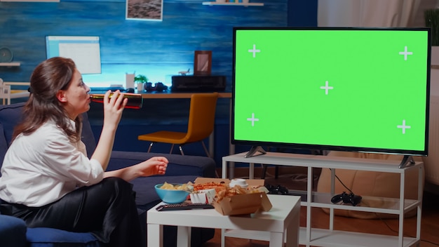 Caucasian woman watching green screen on television