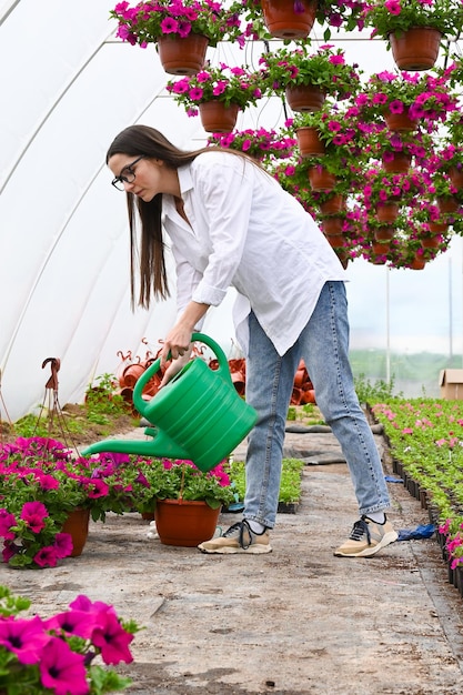 写真 温室で花に水をまく白人女性 植物の世話の概念