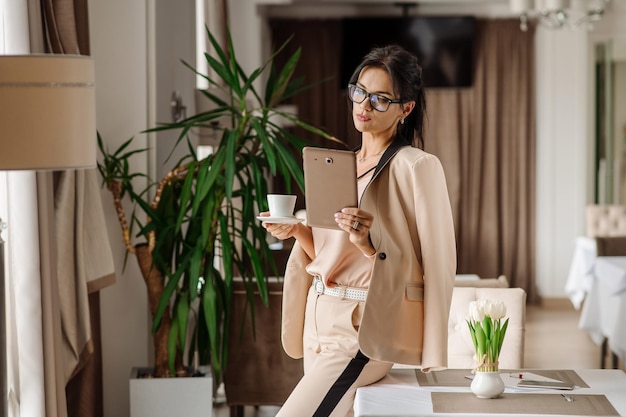 Caucasian woman wearing glasses in suit drinking coffee in the cafe