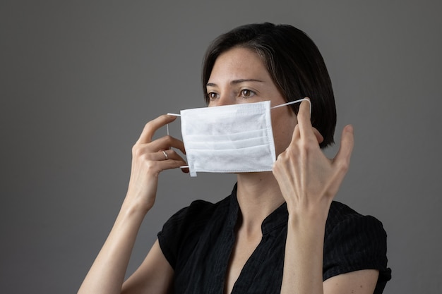 Caucasian woman wearing a white medical mask for protection against contagious disease, coronavirus