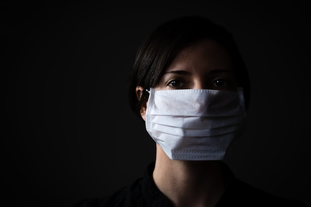 Donna caucasica che indossa una maschera medica bianca per protezione contro il coronavirus