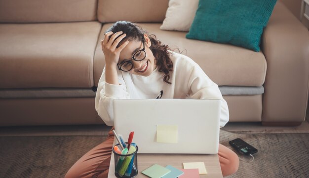 Foto donna caucasica con capelli ricci che sorride al computer portatile mentre scriveva qualcosa