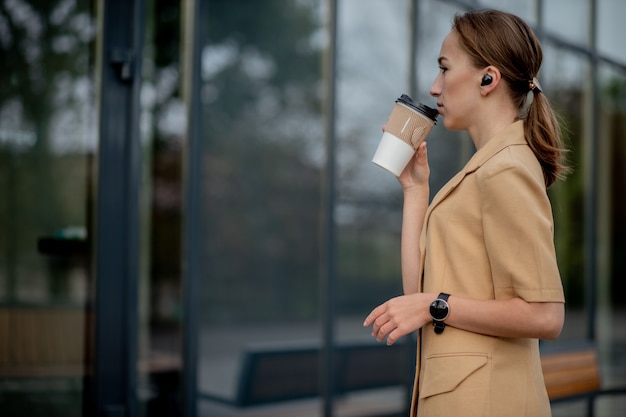 Caucasian woman with smartphone standing against street building