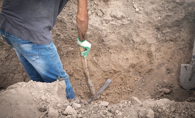 Photo caucasian worker digging a hole.