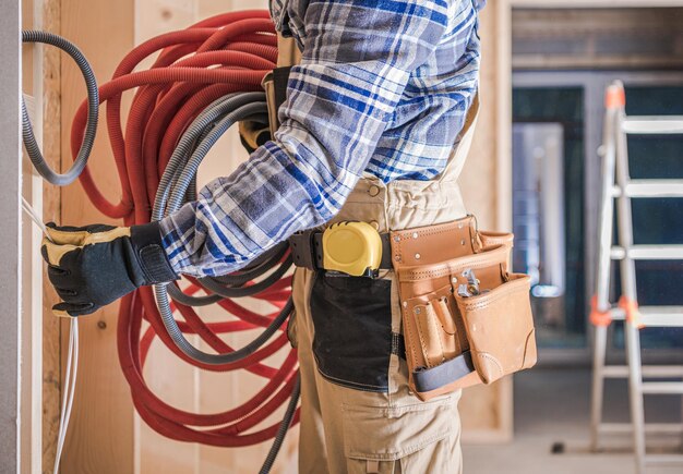 Photo caucasian worker with electric cables installing residential electric lines inside house