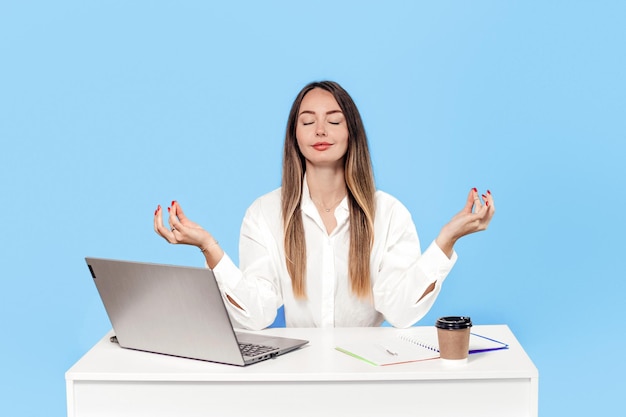 caucasian young business woman meditate at work desk with closed eyes