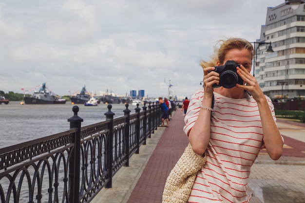 Caucasian young girl taking photo. Front view of a photographer. Photographer concept