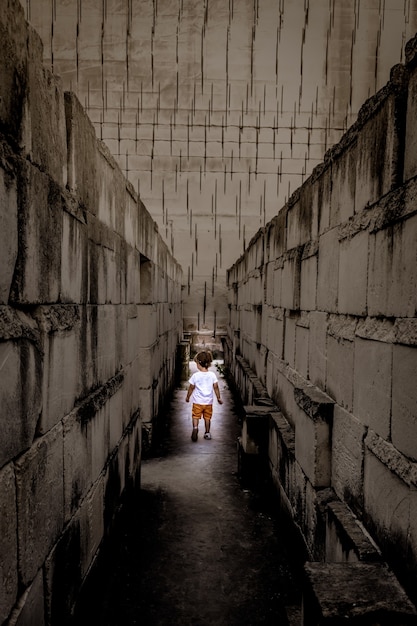 Ragazzino caucasico che cammina con la prospettiva del labirinto. immagine concettuale per situazione pericolosa durante l'infanzia.