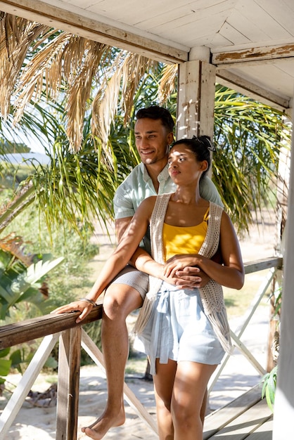 Caucasian young man embracing woman from back and looking away in balcony at cottage. Unaltered, love, together, vacation, tourist resort, lifestyle and enjoyment concept.
