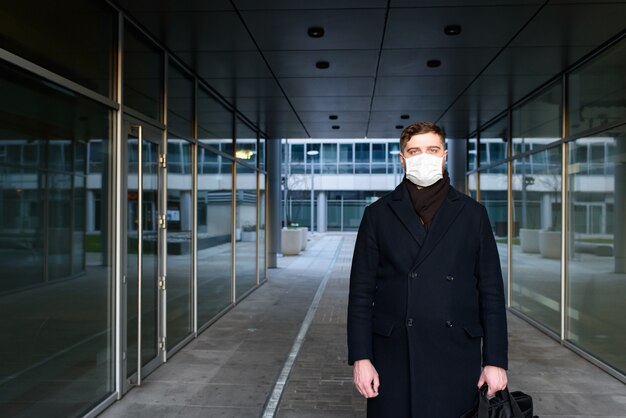 Caucasian young man left office with face mask to work from home