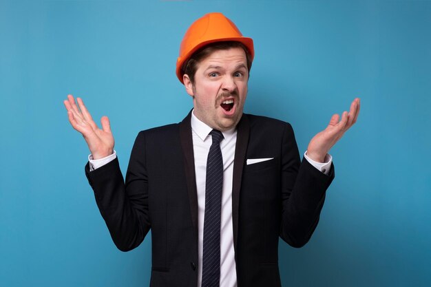 Caucasian young man in orange protective helmet asking what feeling upset