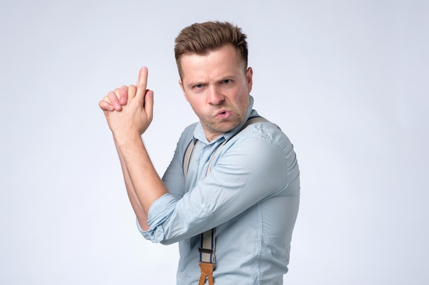 Photo caucasian young man shouting with gun hand gesture