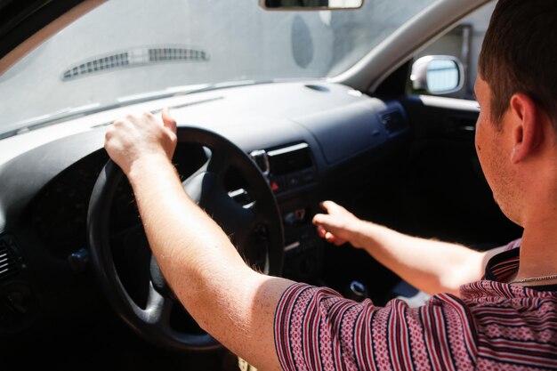 写真 白人男性が車に座って車を運転している20代の男性が開いた窓から銀色の灰色を見ている