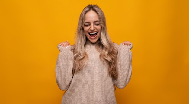 Caucasian young woman emotionally rejoices among yellow background