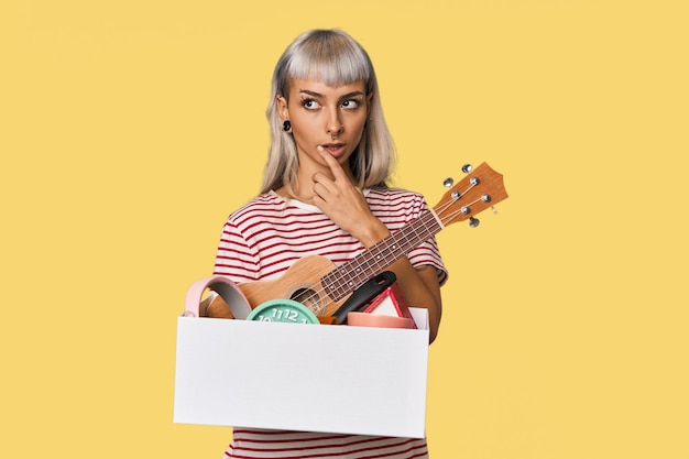 Photo caucasian young woman holding moving box relaxed thinking about something looking at a copy space