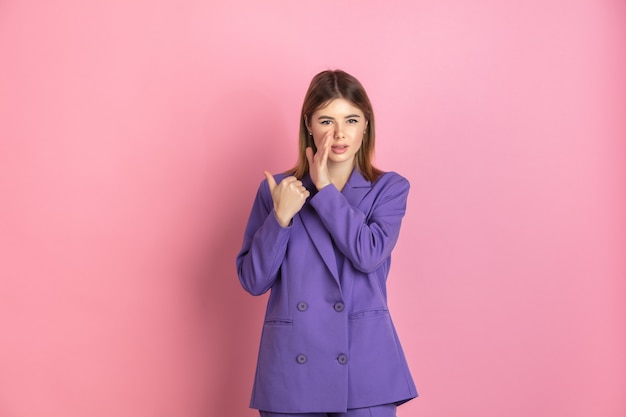 Caucasian young woman's close up portrait on pink studio background, emotional and expressive