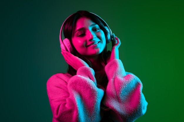Caucasian young woman's portrait on dark studio background in neon