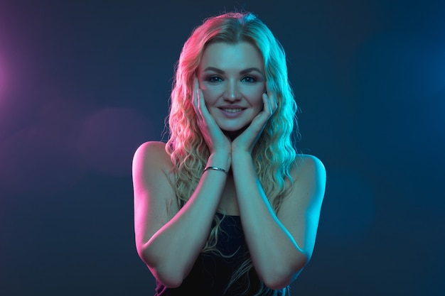 Caucasian young woman's portrait on gradient background in neon light