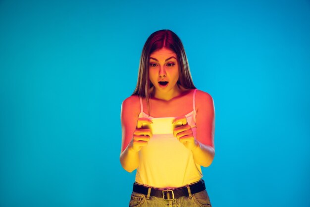 Caucasian young woman's portrait isolated on blue background in neon light