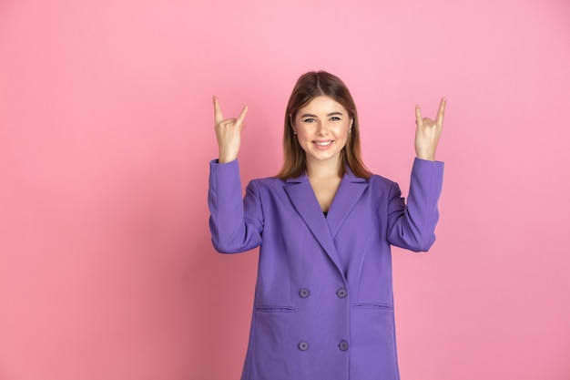 Caucasian young woman's portrait on pink studio background, emotional and expressive