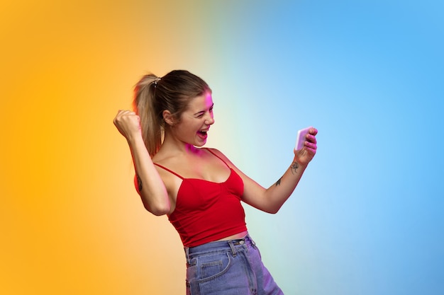 Caucasian young womans portrait on gradient studio background in neon