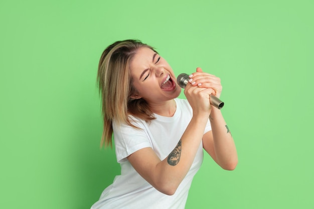 Caucasian young womans portrait on green studio wall