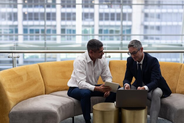 Caucasians business executives talking discussing over laptop while sitting on the sofa