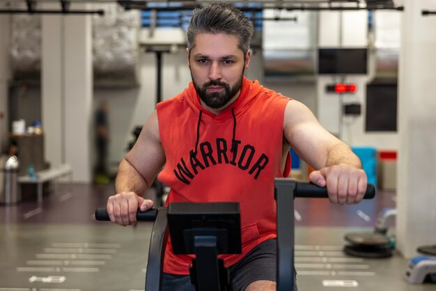 Photo caucasiansportive man in sportswear doing cycling on exercise bikes at the gym cardio workout