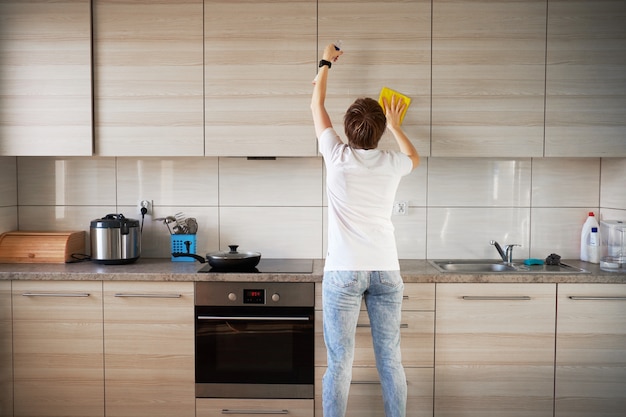 Photo caucasion cleaning girl working at kitchen with yellow rag