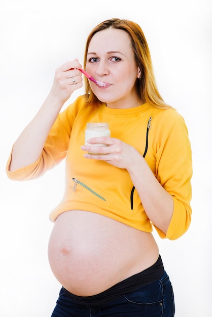 Caucassian pregnant woman with glass of yogurt isolated on white