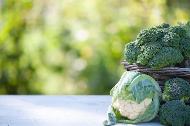 Cauliflower and broccoli in a basket on a natural green background space for text