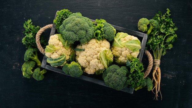Cauliflower and broccoli in a wooden box Fresh vegetables On a wooden background Top view Copy space