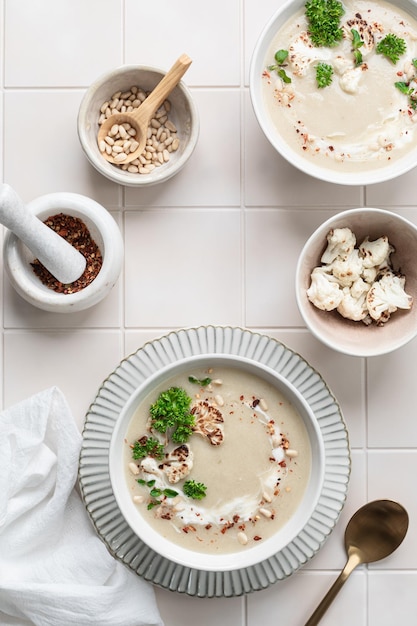 Foto zuppa di crema di cavolfiore con noci di pino in una ciotola su uno sfondo bianco