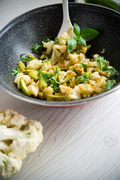 Photo cauliflower fried with zucchini and vegetables in a pan