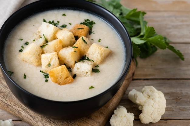 Cauliflower soup in a bowl on wooden table