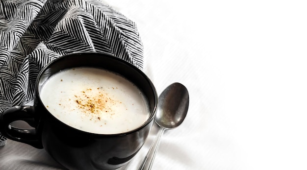 Cauliflower Soup Creme du Barry in black bowl on white background with copy space